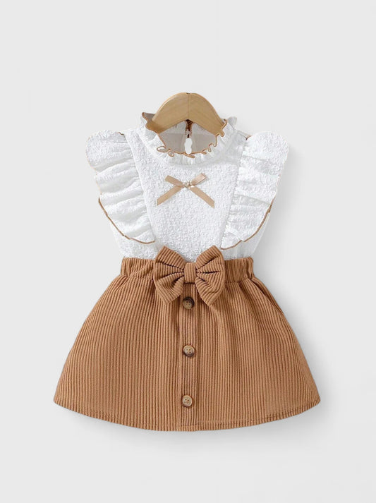White baby girls' ruffle top with tan bow-front corduroy suspender skirt.